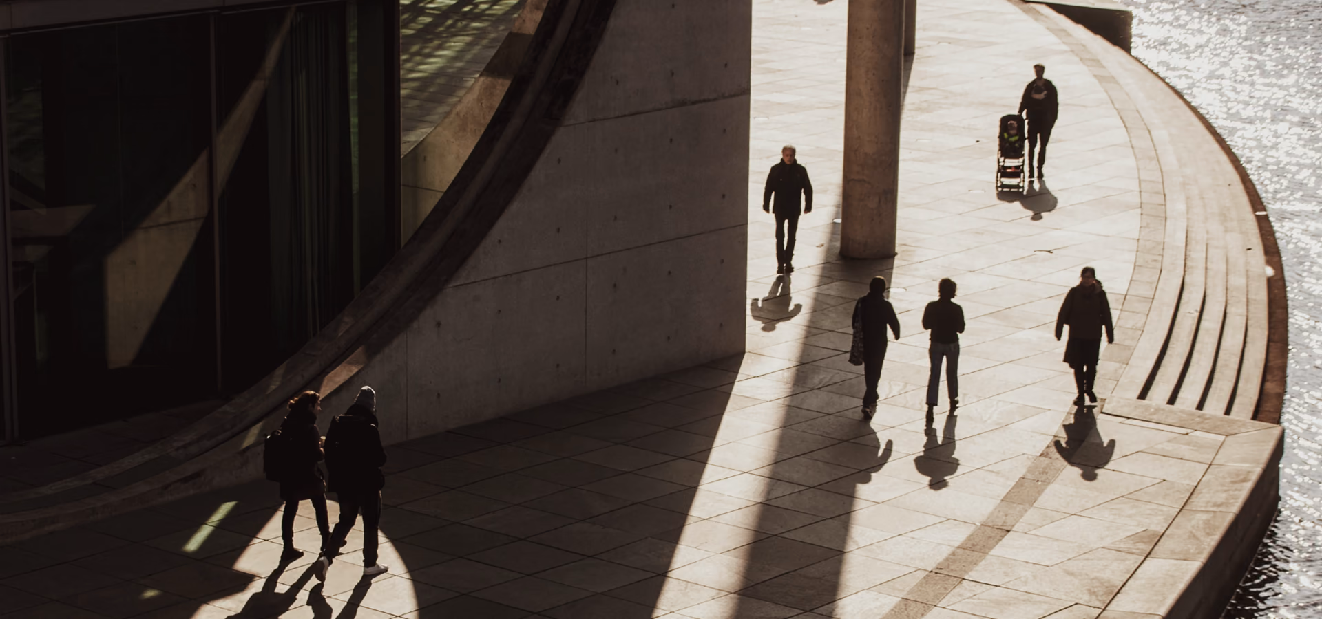 People walking outdoors along a curved concrete building