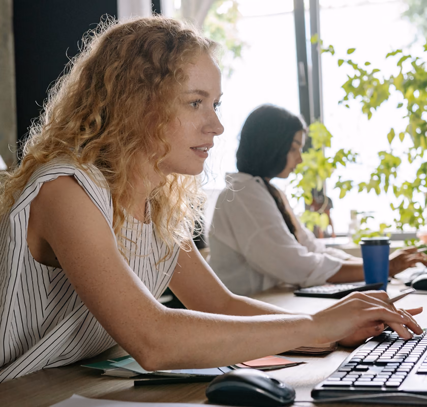 Two colleagues working side by side at their desks in an office